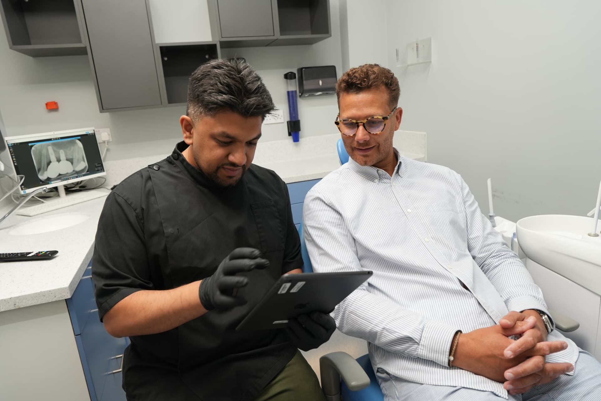 Dr Manraj Sandher going through an Invisalign treatment plan on a tablet with a patient
